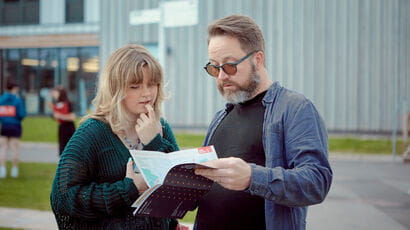 A prospective student and their supporter look at a Campus guide.
