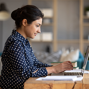 Young professional in a smart polka-dot shirt working at her laptop.