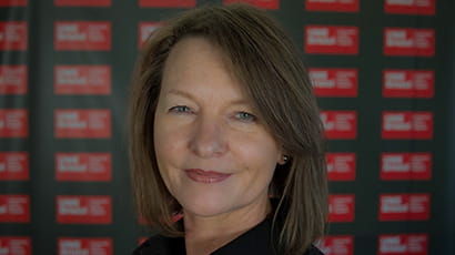 A woman with brown bobbed hair smiles at the camera.